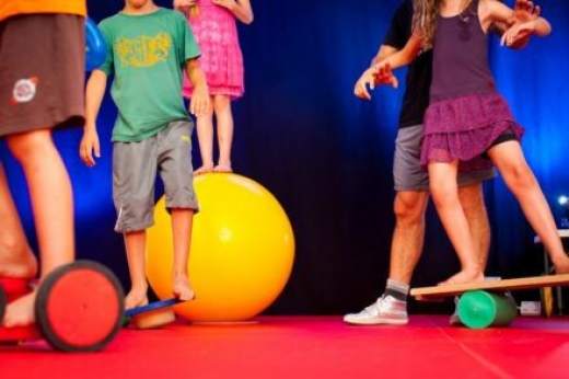 Photo de lactivité scolaire art et expression : initiation au cirque montrant des enfants en équilibre sur des planches et des ballons
