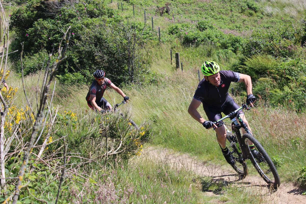 Deux hommes pratiquent le VTT dans la nature, illustrant la rubrique VTT