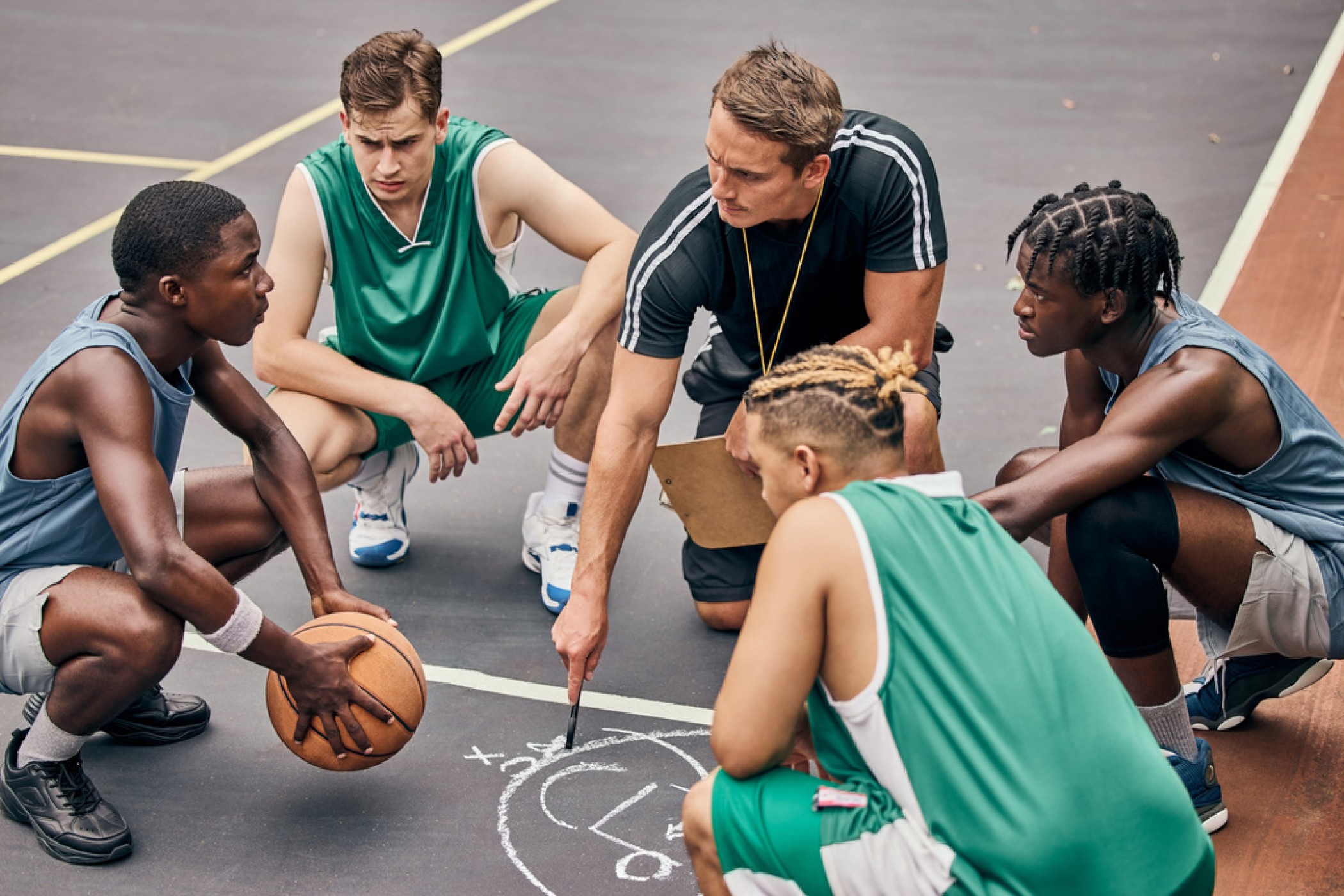 Préparation Basketteurs accroupis en rond discutant et écrivant sur le sol, illustrant la rubrique préparation